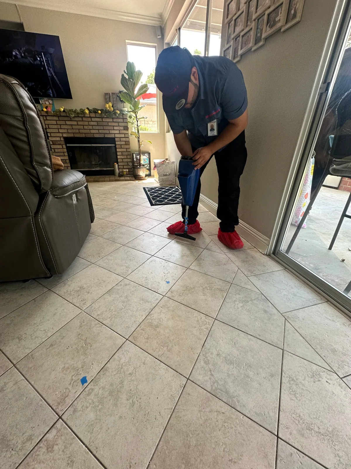 Technician using electronic leak detection equipment on a tile floor