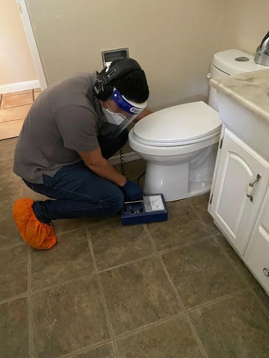 Technician using professional leak detection equipment inside a home