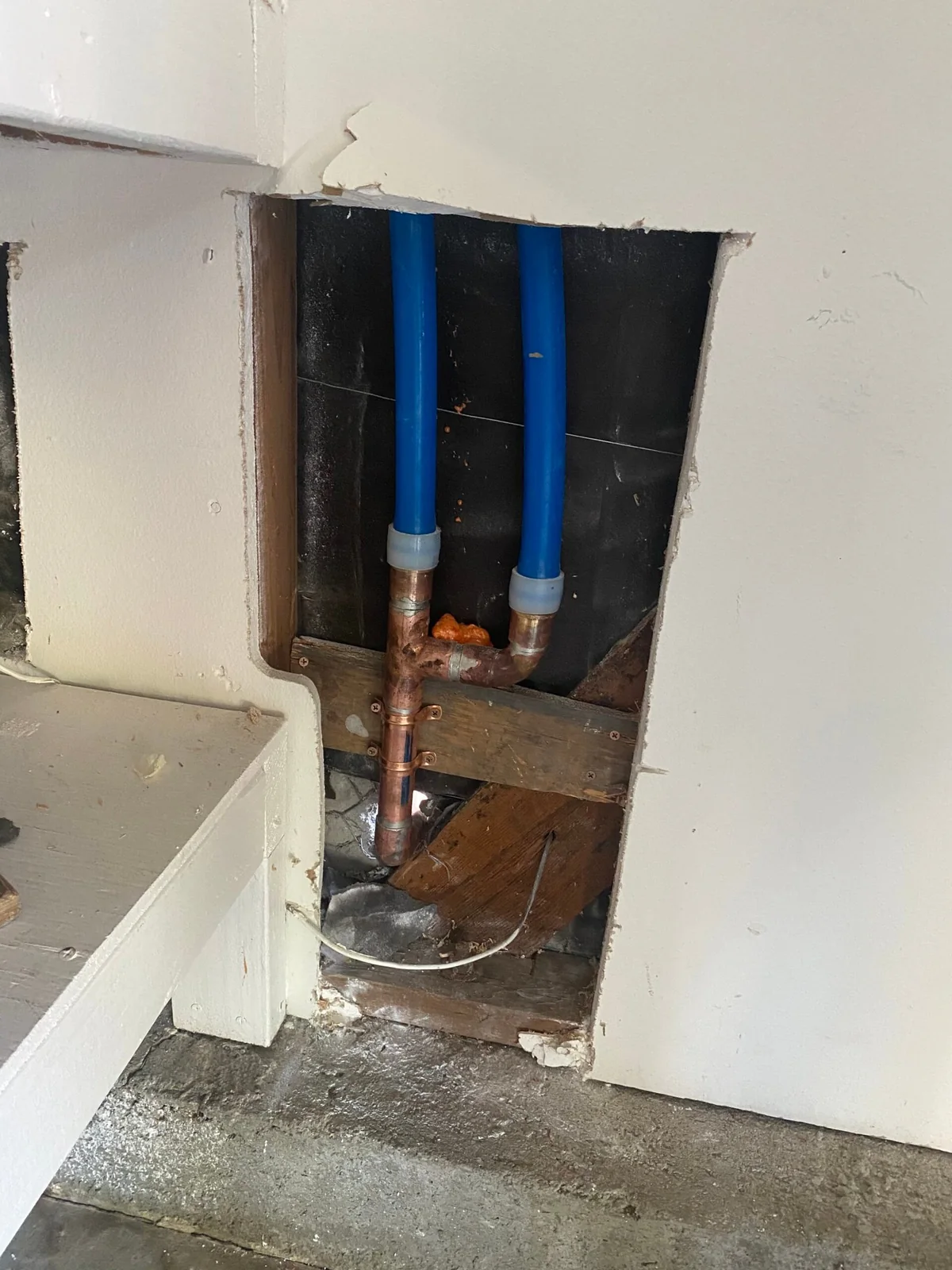 Controlled wall opening exposing water piping after hidden leak symptoms led to inspection