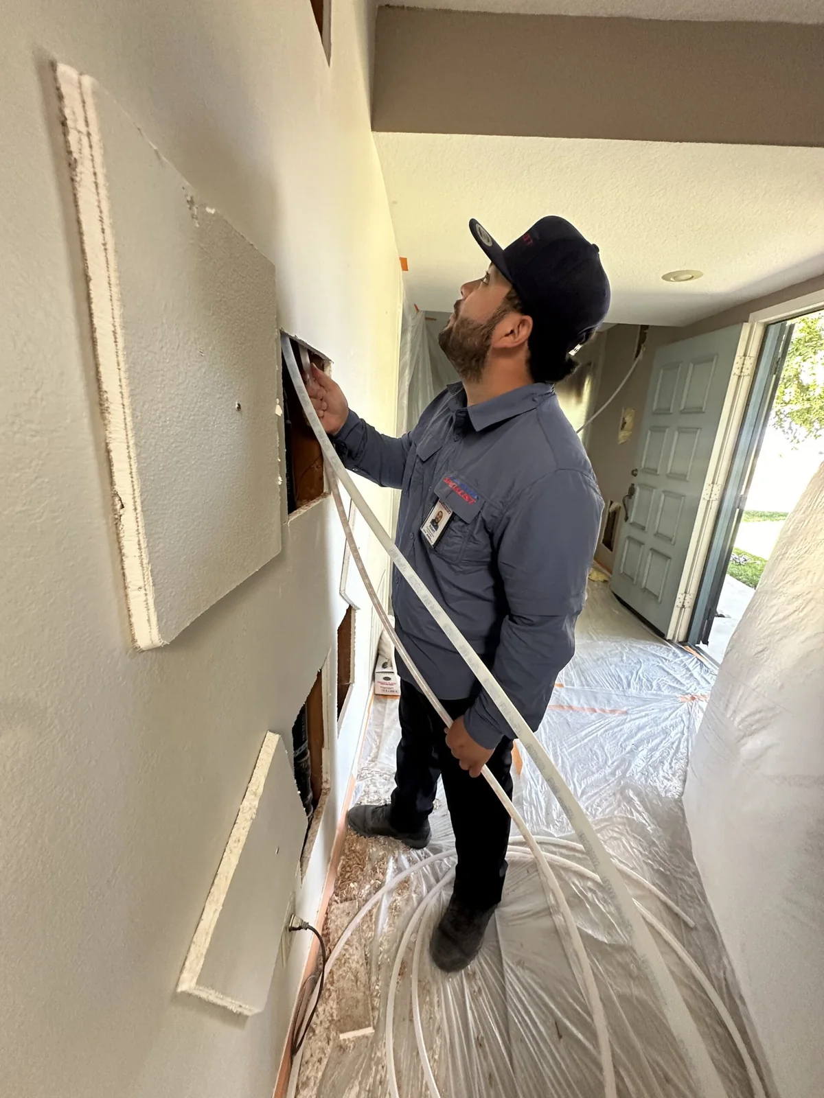 Technician routing new piping through a protected home